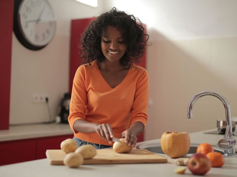 A smiling Black woman preparing fresh food in her kitchen.